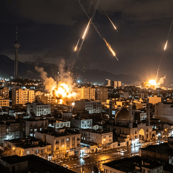 Explosions and rockets launching over a city at night